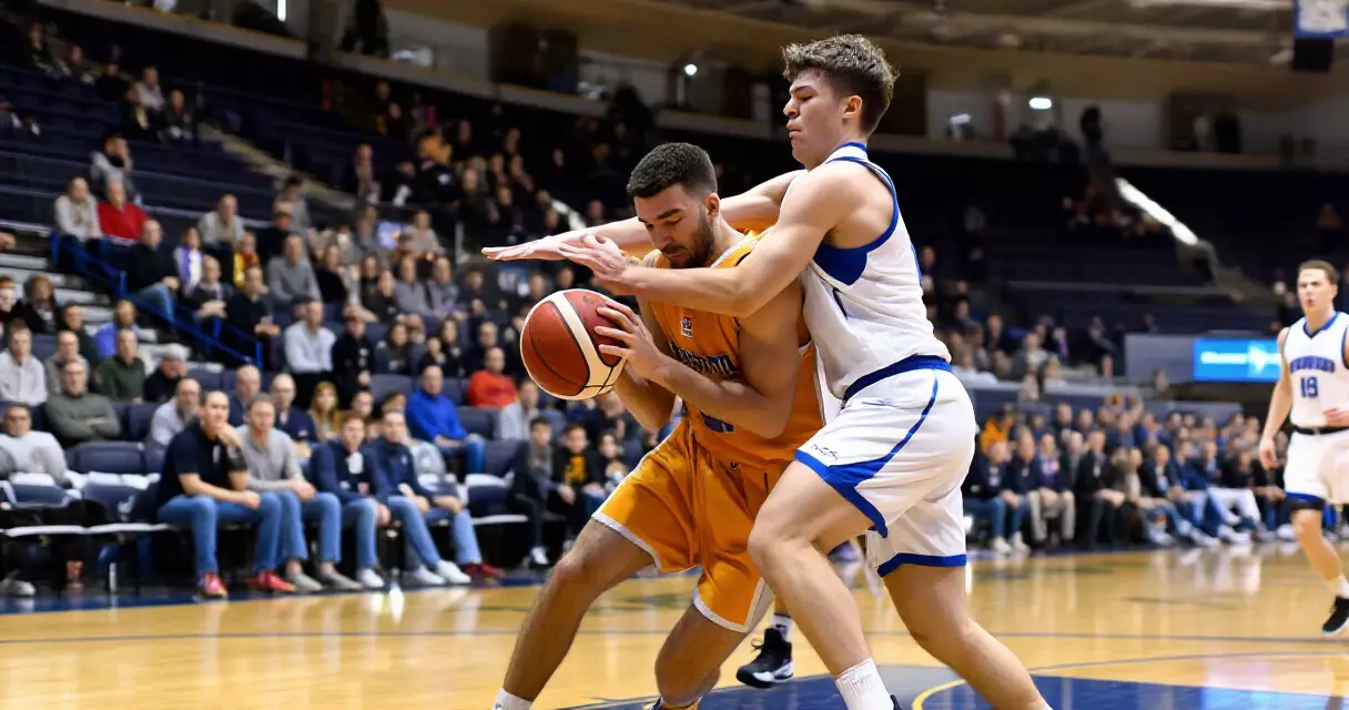 Two basketball players competing in a packed arena