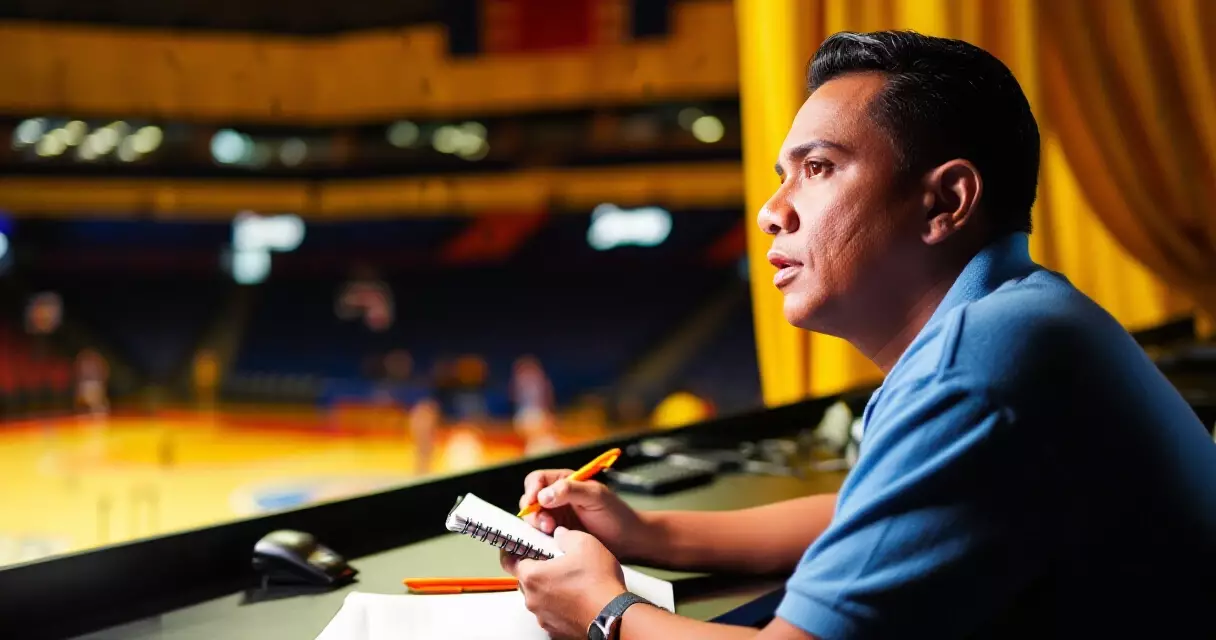 Journalist writing sports news courtside at a basketball game