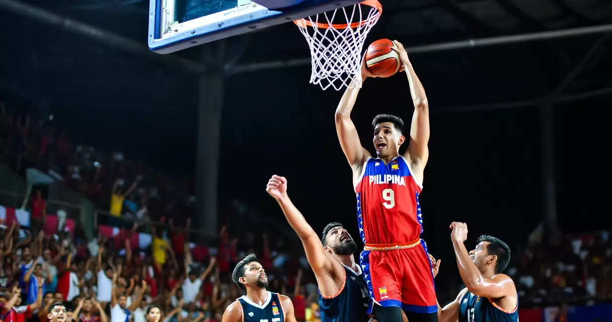 Tall basketball player executing a powerful dunk in the PBA arena