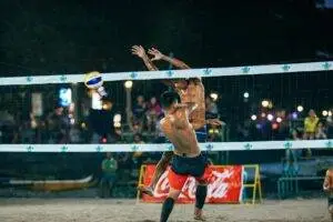 Energetic beach volleyball match under night lights with athletic players.
